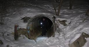 Street outreach on January point in time count, Police officer coming out of a tunnel in the woods with a flash light at night surrounded by snow